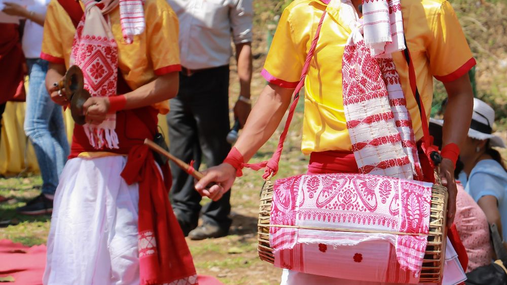 Traditional cultural dance performance with folk musicians in vibrant attire, showcasing local heritage and cultural tourism experience in Northeast India.